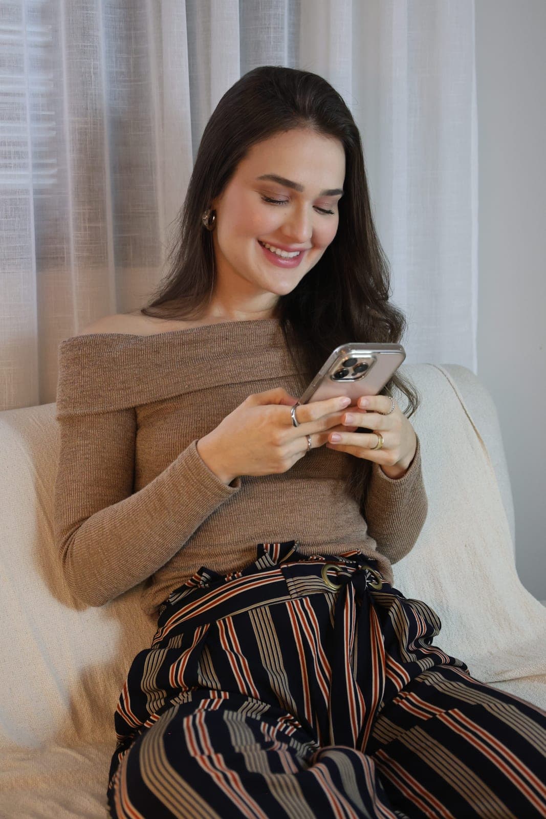 Psicóloga Ana Carolina Crema sorrindo enquanto usa o celular